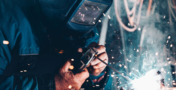 Person in blue coveralls welding